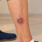 Kleines farbiges Sonnen-Tattoo am Unterschenkel